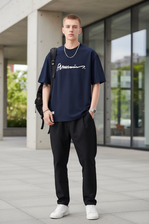 Person wearing a navy blue t-shirt with a logo, holding a black backpack on a light gray background