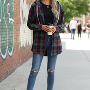 Woman wearing a plaid hoodie and sunglasses, holding a coffee cup.
