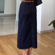 Person wearing dark blue wide-leg jeans indoors on a wooden floor.