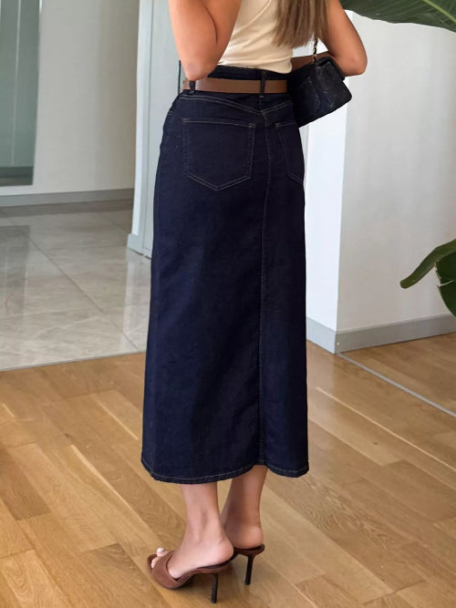 Person wearing dark blue wide-leg jeans indoors on a wooden floor.
