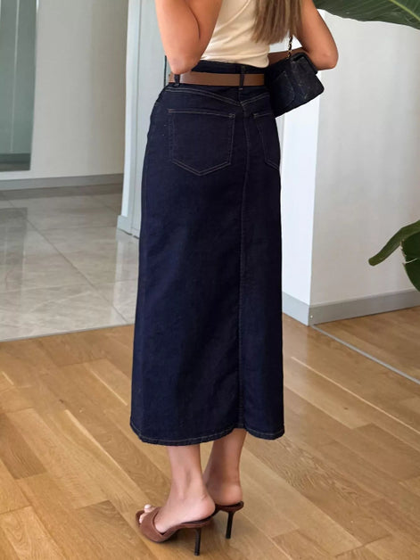 Person wearing dark blue wide-leg jeans indoors on a wooden floor.