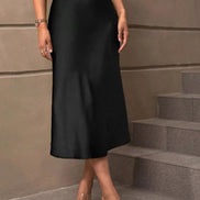 Person wearing a black skirt standing on steps against a beige wall