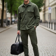 A man wearing an olive green two-piece tracksuit consisting of a long-sleeve button-up shirt and matching jogger pants, 