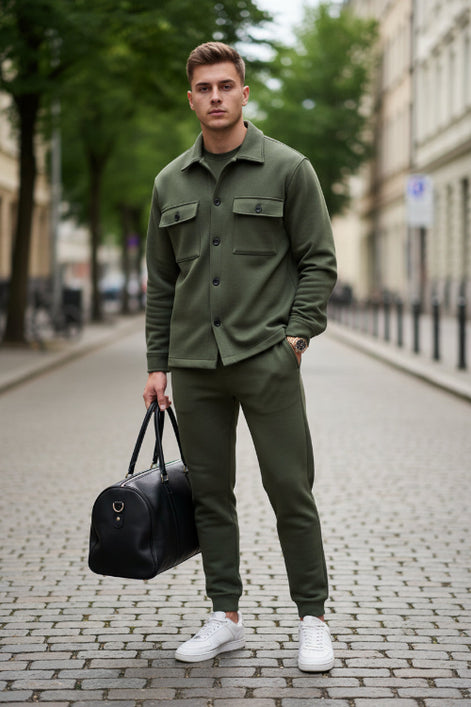 A man wearing an olive green two-piece tracksuit consisting of a long-sleeve button-up shirt and matching jogger pants, 