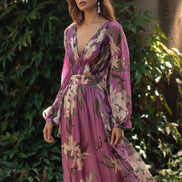Woman wearing a long floral dress with a blurred natural background