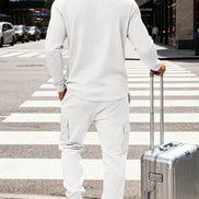 A man viewed from behind wearing a matching white textured long-sleeve top and jogger pants, 