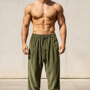 A man wearing loose olive green drawstring sweatpants and white sneakers, 
