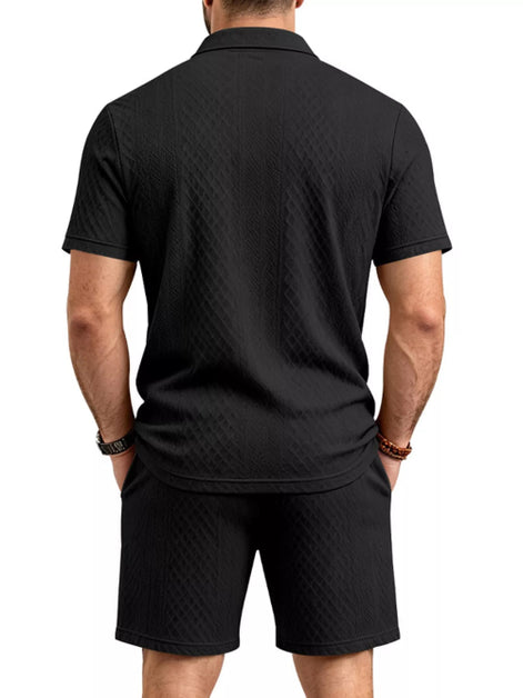 A man viewed from the back wearing a black short-sleeve polo shirt and matching black shorts, 