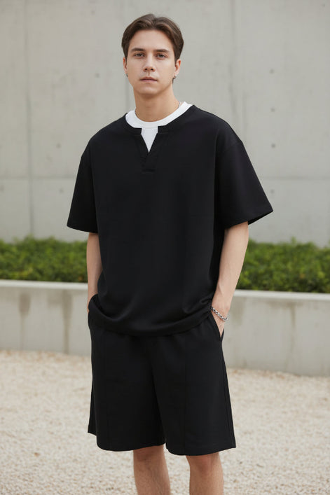Person wearing a black outfit with a white collar on a plain background