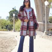 Woman wearing a plaid coat and blue jeans standing outdoors 
