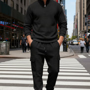 A man wearing a matching black textured quarter-zip pullover and jogger 