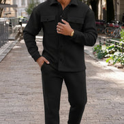 A man wearing a black long-sleeve button-up shirt and matching black jogger pants, 
