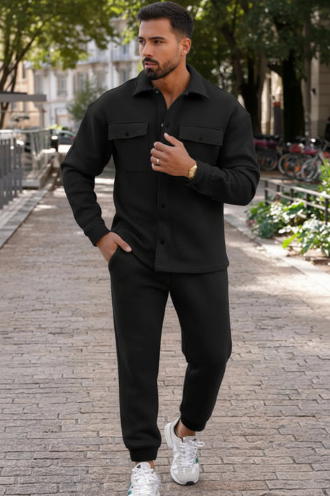 A man wearing a black long-sleeve button-up shirt and matching black jogger pants, 