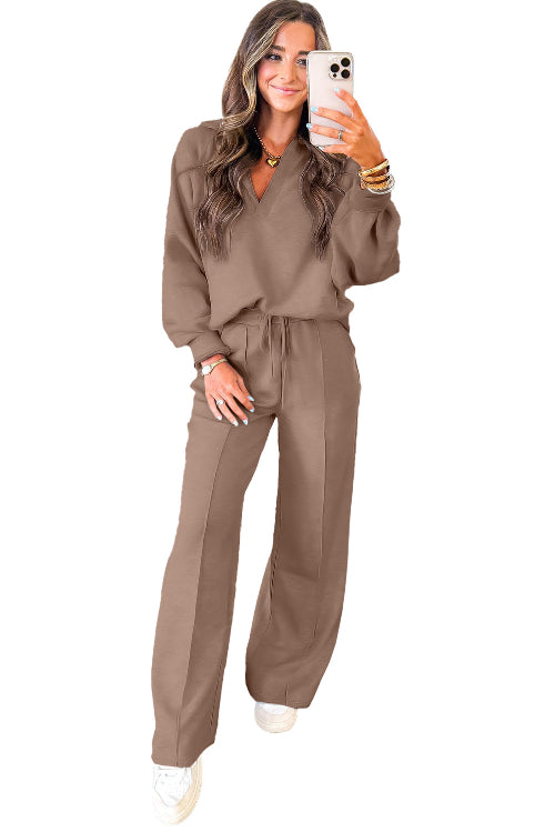 Woman wearing a brown tracksuit holding a phone on a white background