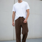 Brown corduroy pants worn by a person on a white background