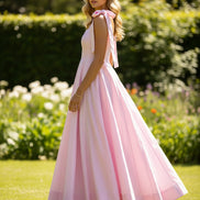 Pink dress with bow straps worn by a person against a plain background