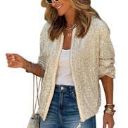Woman wearing a sparkly beige cardigan, white top, and blue jeans with sunglasses on a white background