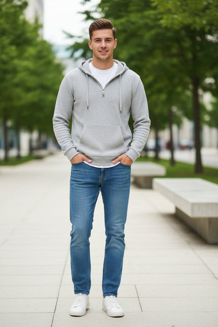 Person wearing a gray textured hoodie with a zipper, standing against a white background