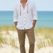 Man wearing a white button-up shirt with a beach background
