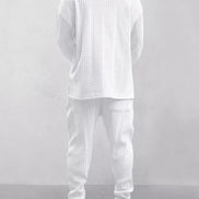 A person shown from the back wearing a matching white textured knit lounge set consisting of a long-sleeve top and jogger pants, 