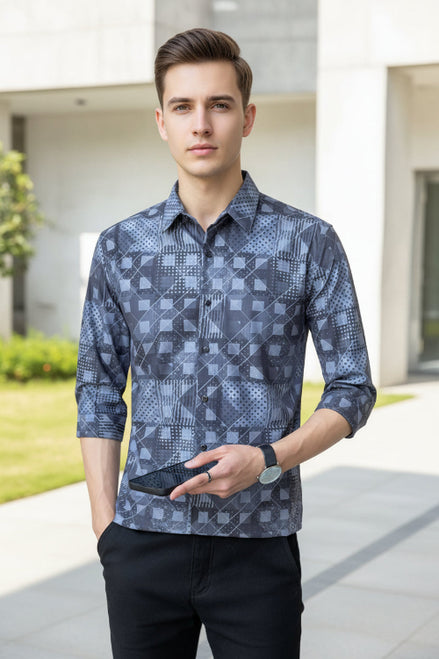 Person wearing a patterned shirt holding a phone with a neutral background