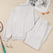 Gray sweatshirt and pants set with a tennis racket and newspaper on a beige background