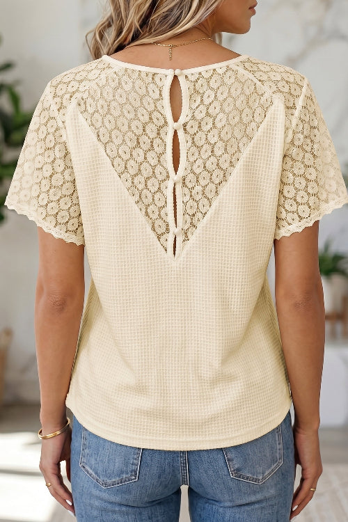Beige lace top worn by a person with a blurred indoor background