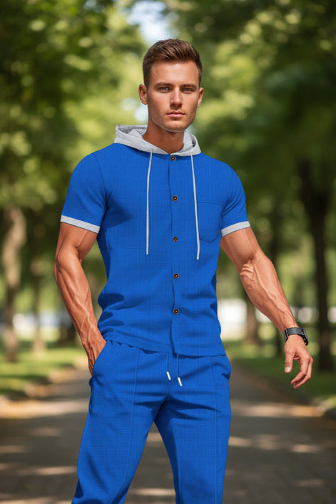 A man wearing a matching royal blue two-piece tracksuit with a short-sleeve button-front hoodie top 
