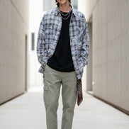 Person wearing a plaid shirt over a black top on a white background