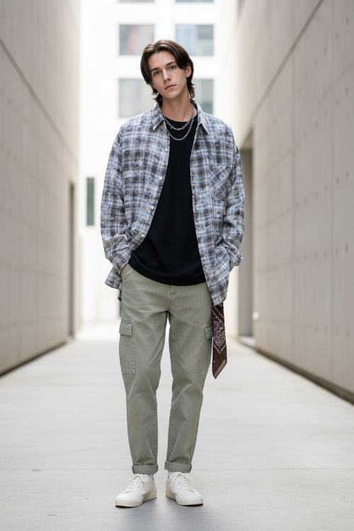Person wearing a plaid shirt over a black top on a white background