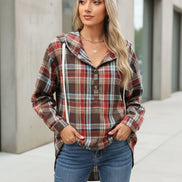 Woman wearing a plaid jacket standing outdoors.