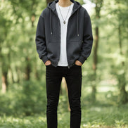 Person wearing a dark gray hoodie on a light gray background