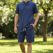 Blue shirt and pants set on hangers against a white background
