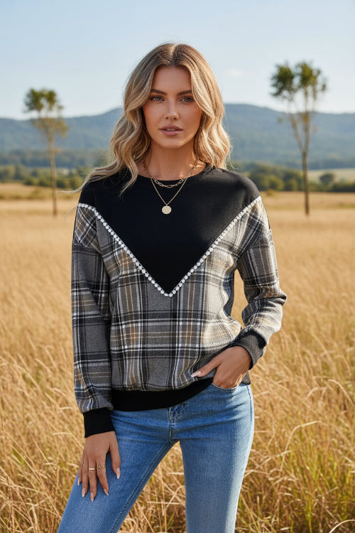 Person wearing a black and plaid long-sleeve top with a white background