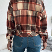 Person wearing a plaid shirt and blue jeans sitting on a couch.