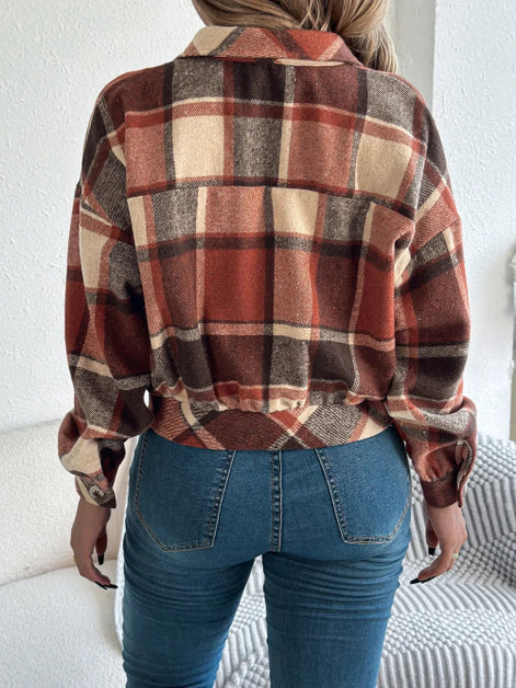 Person wearing a plaid shirt and blue jeans sitting on a couch.