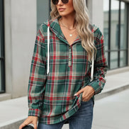 Woman wearing a plaid shirt and jeans, holding a coffee cup.