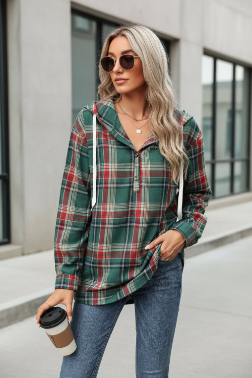 Woman wearing a plaid shirt and jeans, holding a coffee cup.