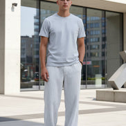 White ribbed corduroy pants with a vertical stripe texture, featuring a side pocket with a black brand label 