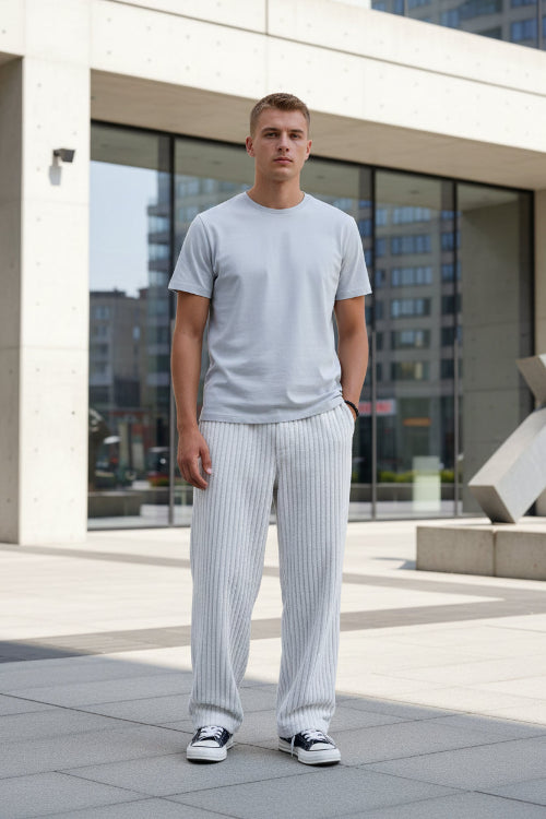 White ribbed corduroy pants with a vertical stripe texture, featuring a side pocket with a black brand label 