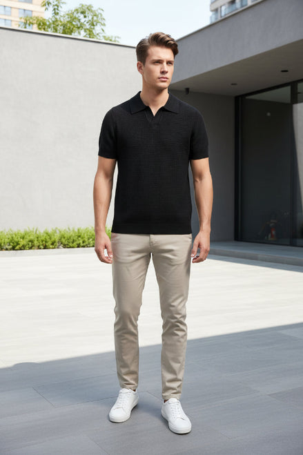 Black polo shirt on a hanger against a gray background
