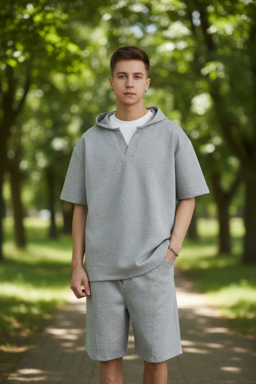 Person wearing a gray outfit with a plain background
