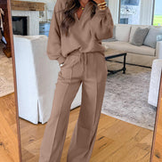Woman taking a mirror selfie wearing a brown outfit in a living room.