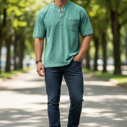 Man wearing a green short-sleeve henley shirt with a pocket on a white background