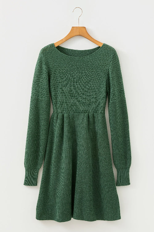 Green knitted dress on a wooden hanger against a white background
