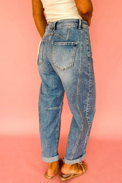Person wearing blue jeans against a pink background