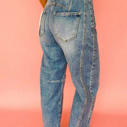 Person wearing blue jeans against a pink background
