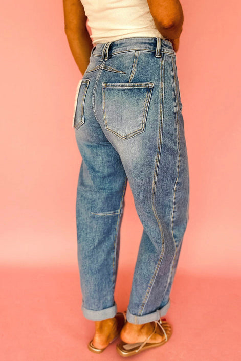 Person wearing blue jeans against a pink background