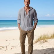Man wearing a light gray hoodie with a beach in the background
