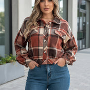 Person wearing a plaid shirt and blue jeans sitting on a couch.